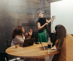 three women engaged in a collaborative discussion in a small meeting room